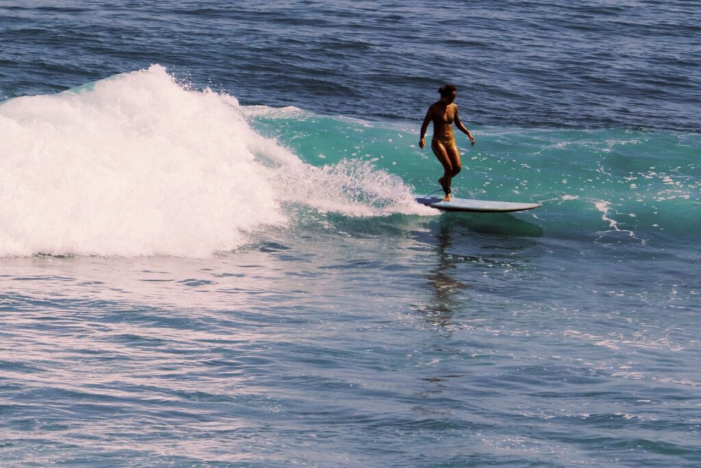 Close up view of someone surfing a wave in Bali. Water is crystal and blue. To showcase a must do in a one week bali itinerary.