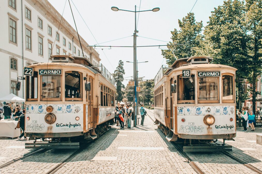 Two iconic yellow trams pass each other on a charming cobblestone street in Porto, Portugal, with historic buildings in the background. A perfect scene to enjoy while searching for the best breakfast in Porto Portugal.